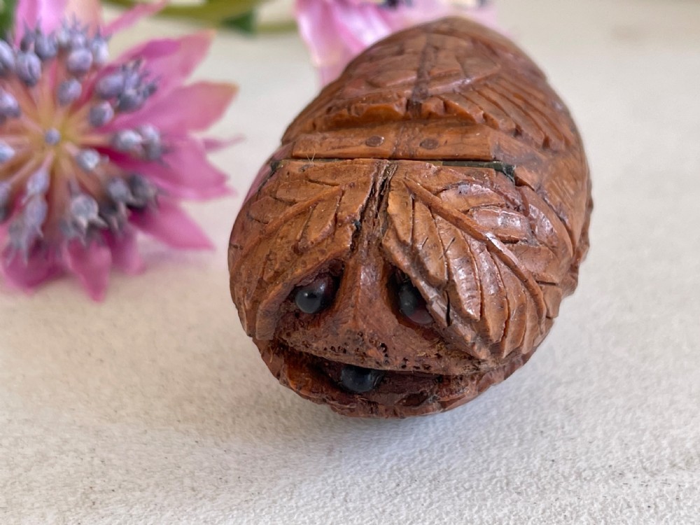 A small antique hand-carved coquilla nut snuff box shaped as a bugbear figure with detailed leaf engravings and a tiny metal hinge. View IX