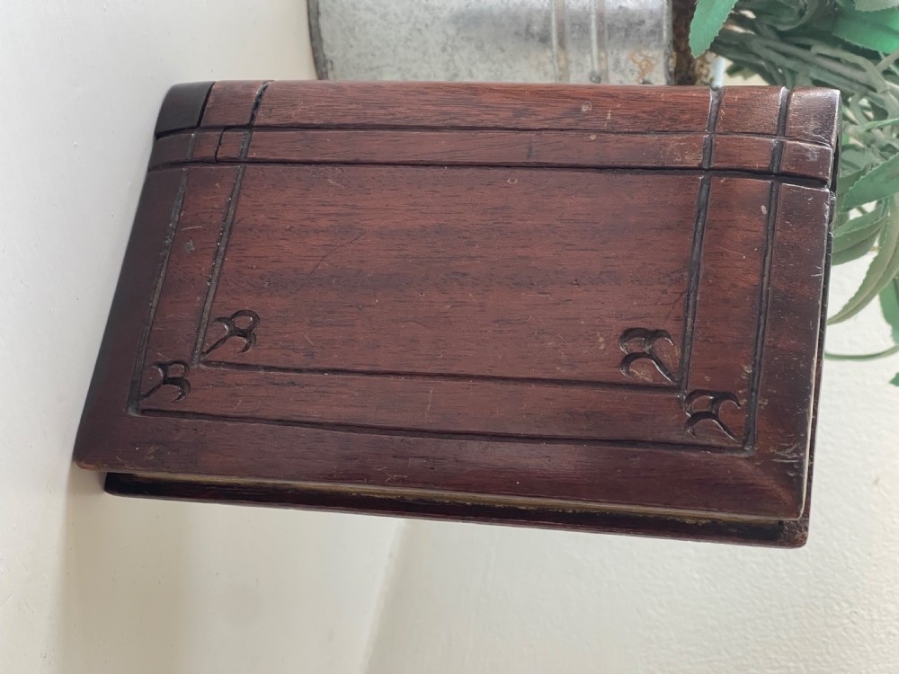 A dark brown carved wooden box designed in the shape of a book with decorative corner engravings. View III
