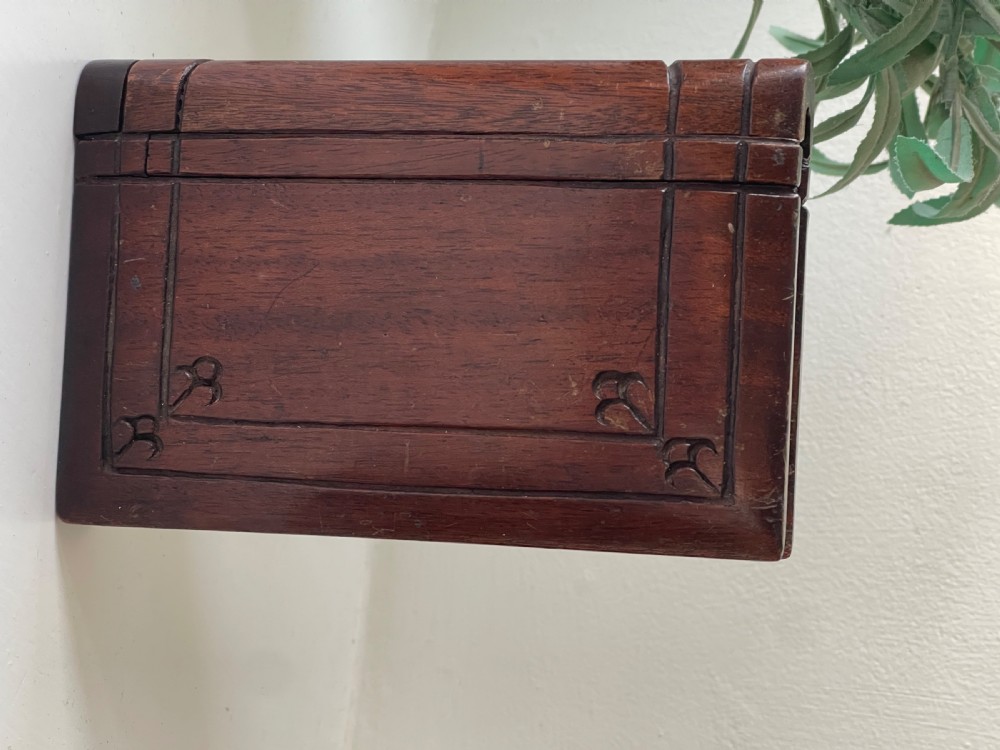 A dark brown carved wooden box designed in the shape of a book with decorative corner engravings. View VI