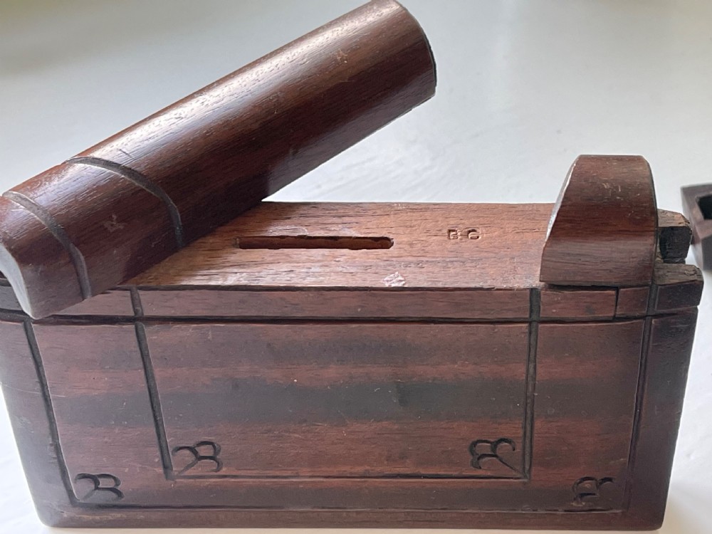 A dark brown carved wooden box designed in the shape of a book with decorative corner engravings. View VII