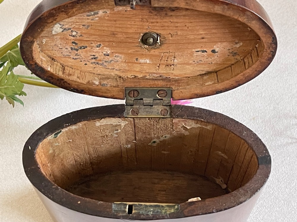 An eighteenth-century Georgian oval mahogany tea caddy featuring polished grain, a bone keyhole escutcheon, and a brass ring handle on the hinged top. View III