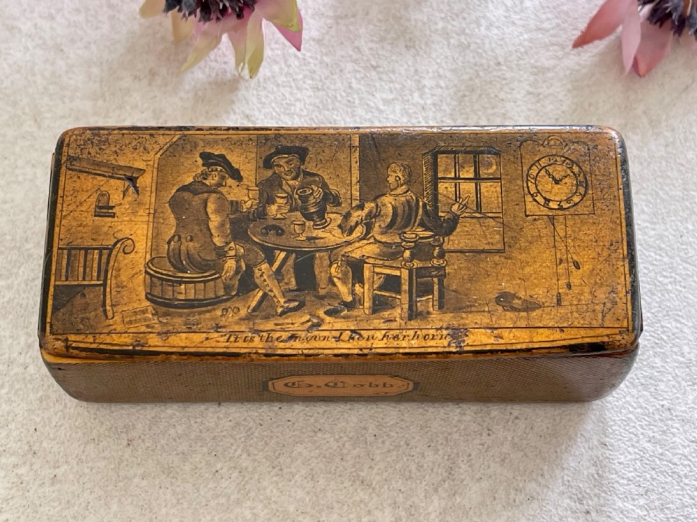 A small rectangular antique wooden snuff box featuring penwork illustrations of men in a tavern on the lid and a central name tag inscribed G. Cobb on the front. View II