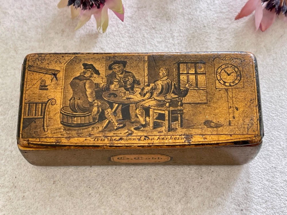 A small rectangular antique wooden snuff box featuring penwork illustrations of men in a tavern on the lid and a central name tag inscribed G. Cobb on the front. View VII