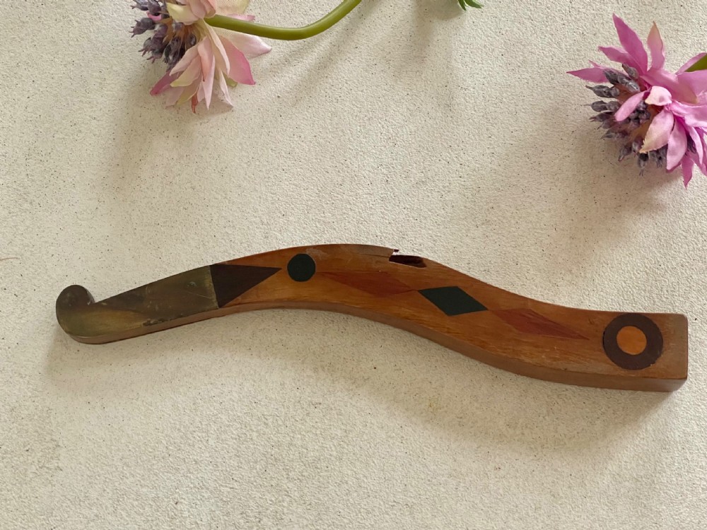 A curved antique wooden knitting sheath featuring geometric marquetry inlays and a small metal-ended aperture. View II