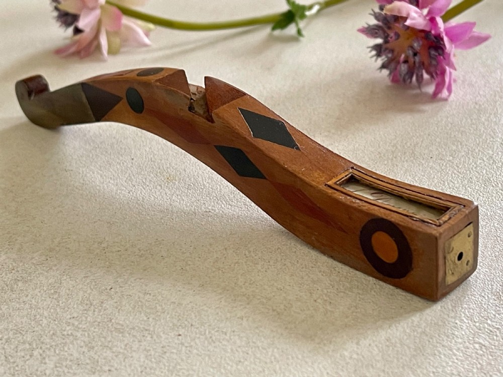 A curved antique wooden knitting sheath featuring geometric marquetry inlays and a small metal-ended aperture. View VI