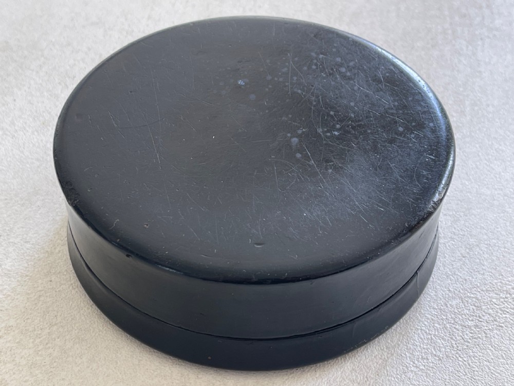 A circular black lacquered papier-mache snuff box lid featuring a hand-painted classical portrait of a bearded man wearing a green headband. View IV