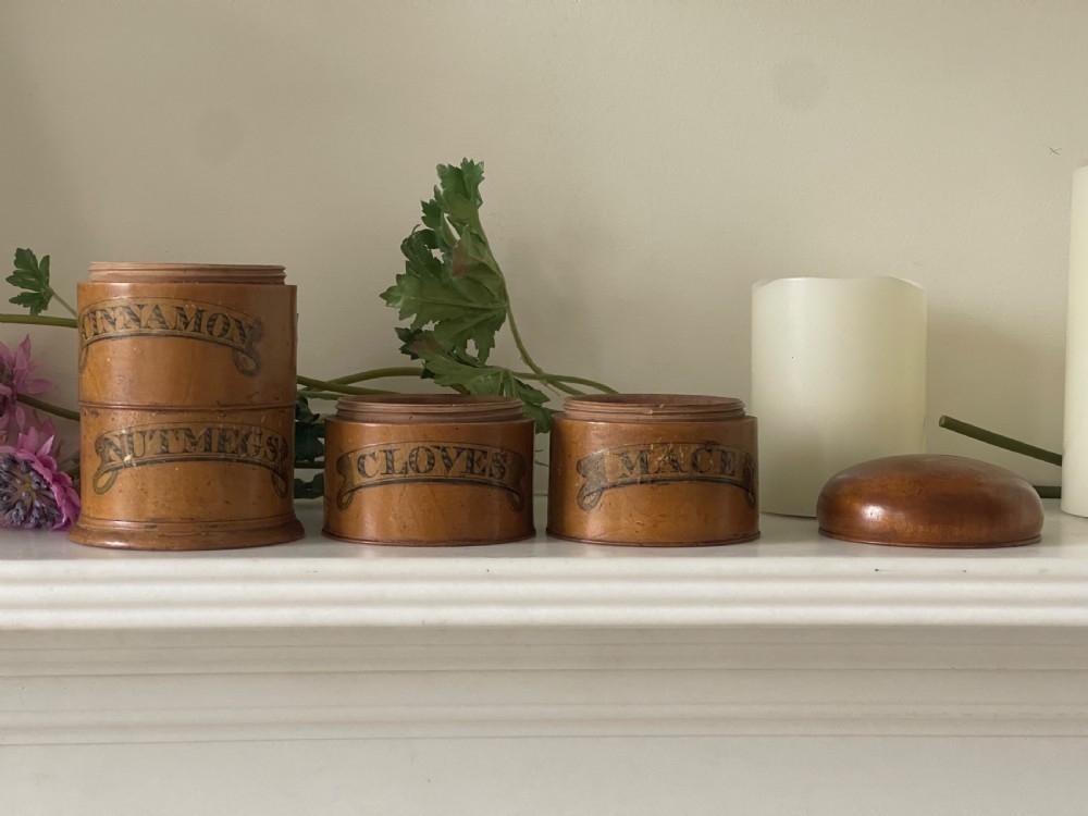 A four-tier turned wooden spice tower featuring black printed banner labels reading Mace, Cloves, Cinnamon, and Nutmegs. View II