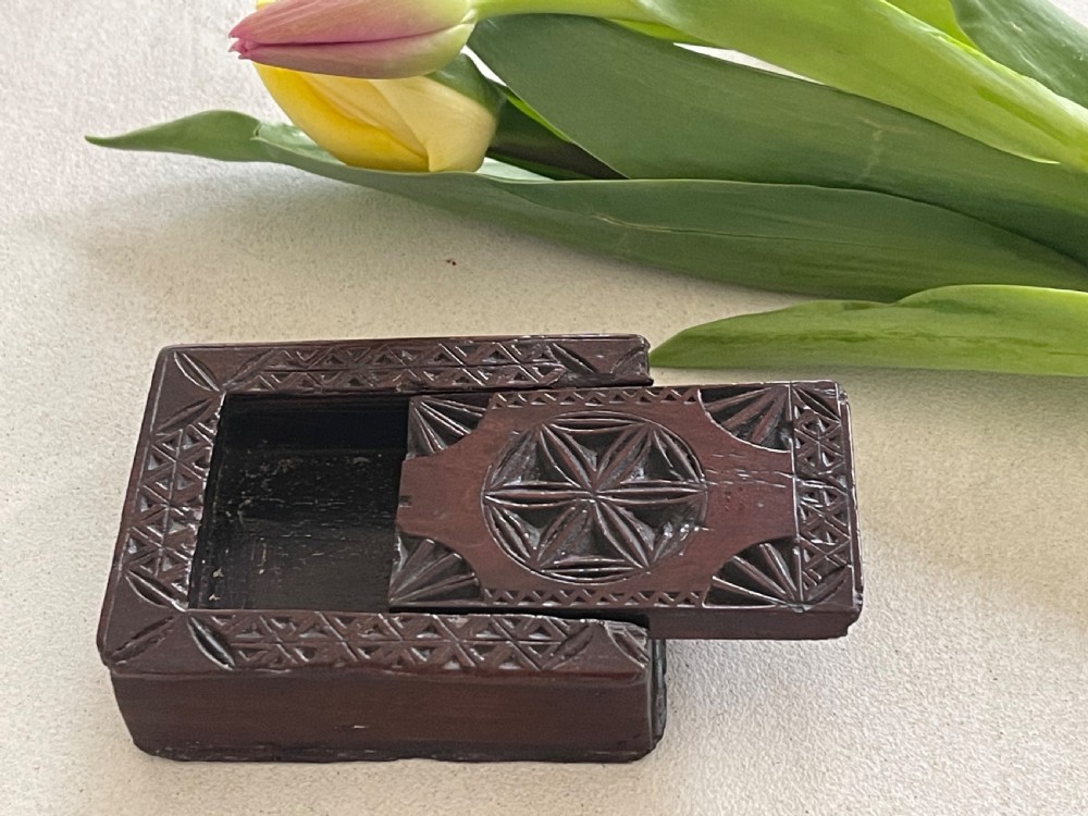 A dark brown chip-carved wooden snuff box shaped like a miniature book with geometric star carvings and a light wood heart inlay on the spine. View III