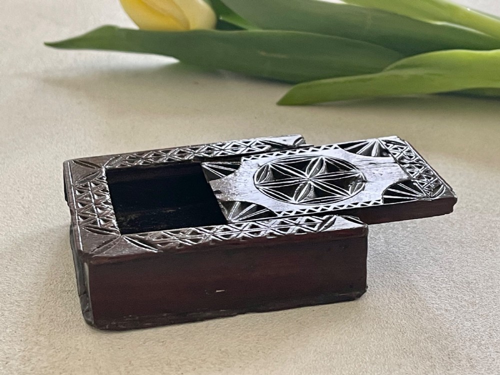A dark brown chip-carved wooden snuff box shaped like a miniature book with geometric star carvings and a light wood heart inlay on the spine. View IV