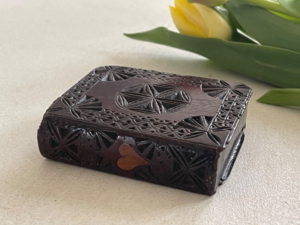 A dark brown chip-carved wooden snuff box shaped like a miniature book with geometric star carvings and a light wood heart inlay on the spine. View VI
