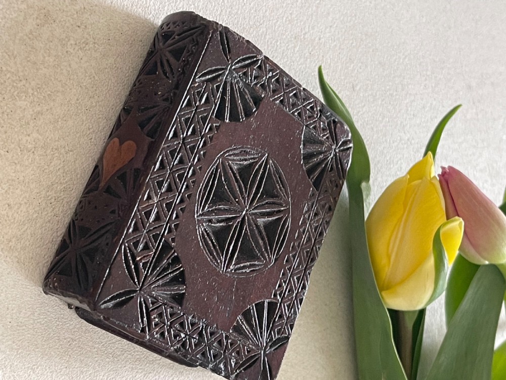 A dark brown chip-carved wooden snuff box shaped like a miniature book with geometric star carvings and a light wood heart inlay on the spine. View VIII