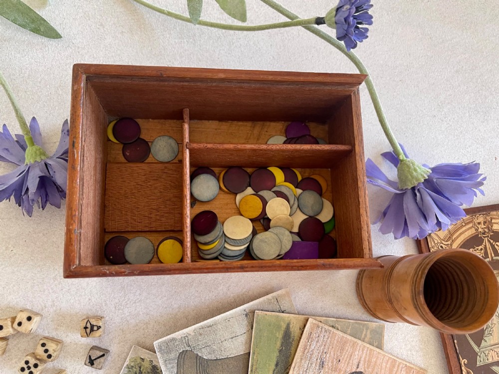 A rectangular wooden game box with a detailed printed paper lid depicting a bell, a hammer, floral garlands, and classical scrollwork. View IV