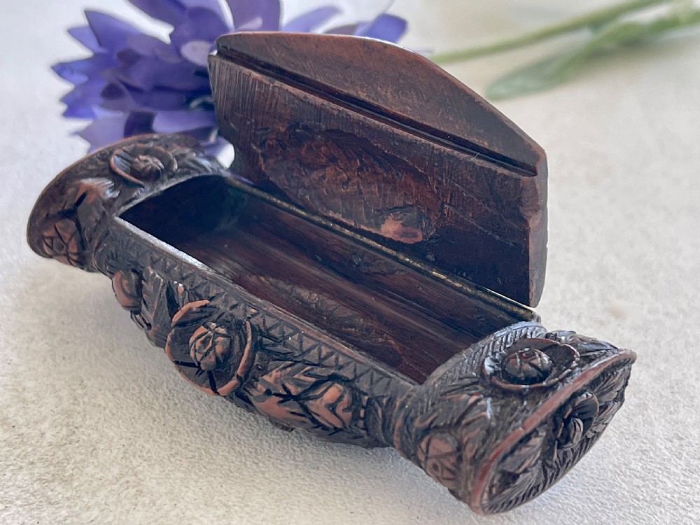 A detailed carved dark brown coquilla nut snuff box featuring a central relief medallion of a female profile surrounded by decorative foliage patterns. View III