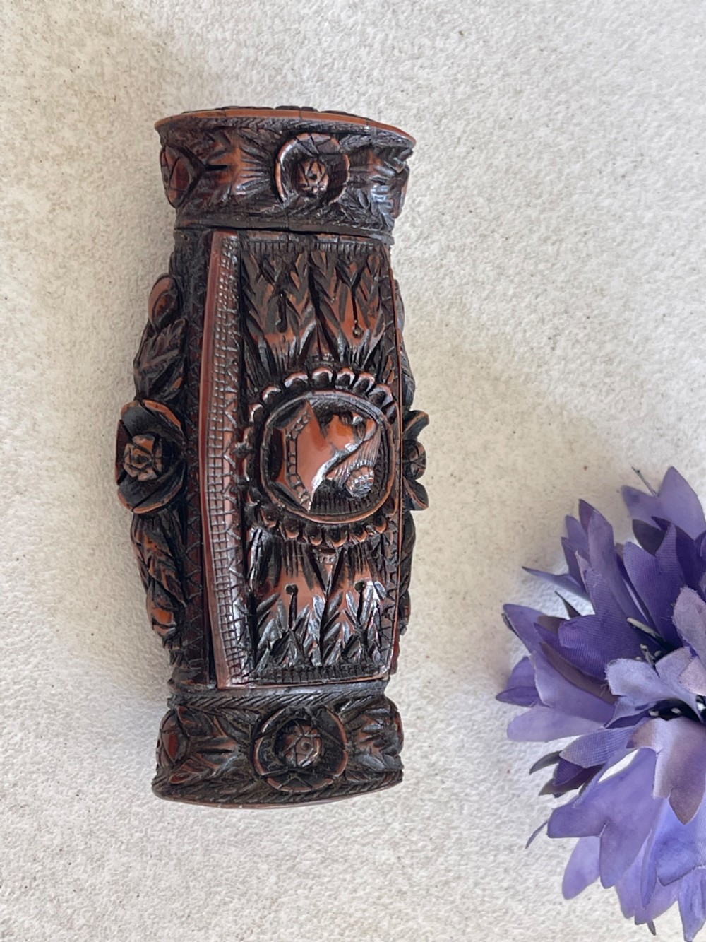 A detailed carved dark brown coquilla nut snuff box featuring a central relief medallion of a female profile surrounded by decorative foliage patterns. View IV