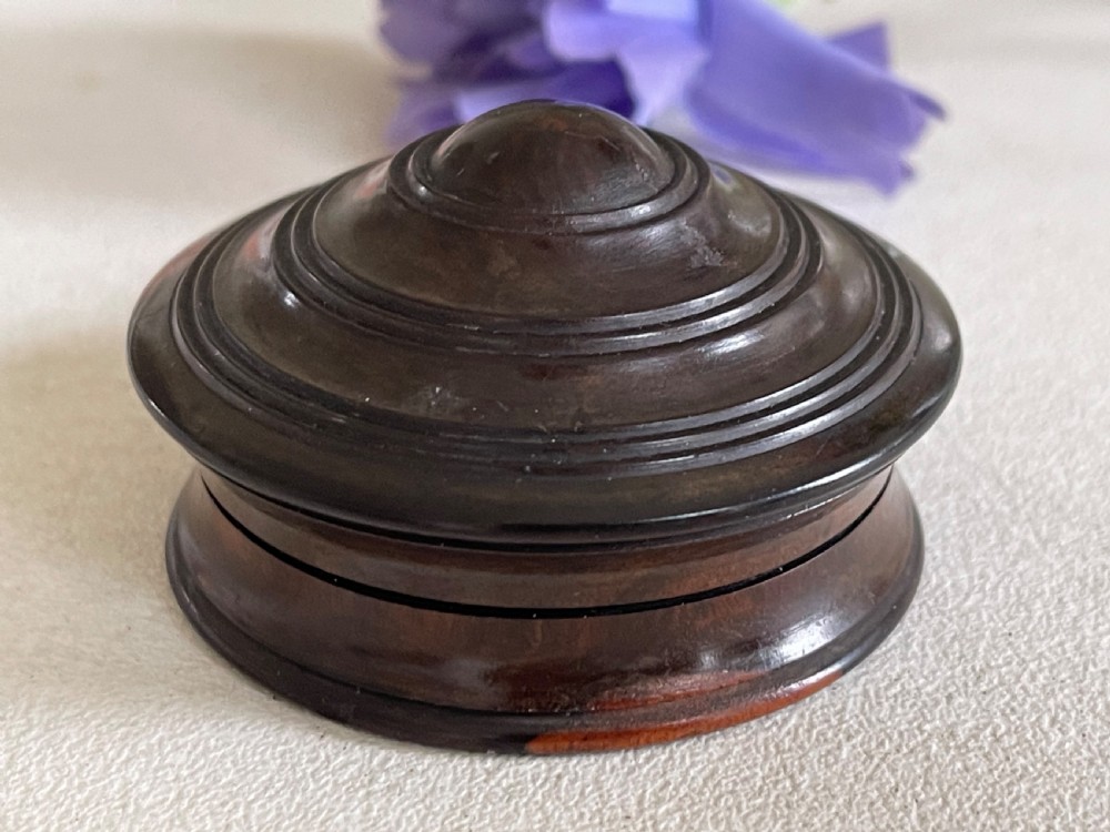 A small, circular antique turned wood case with a domed, stepped lid designed to hold a travelling compass sundial. View V