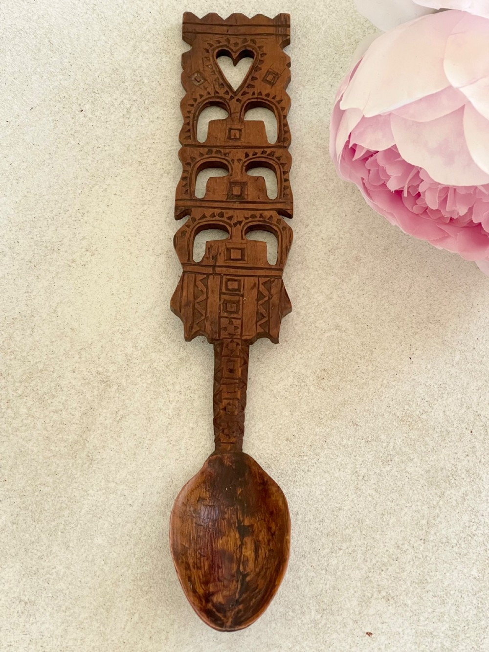 A hand-carved dark wood Welsh lovespoon with geometric chip-carved detailing, a pierced heart cutout at the top, and a smoothed spoon bowl.