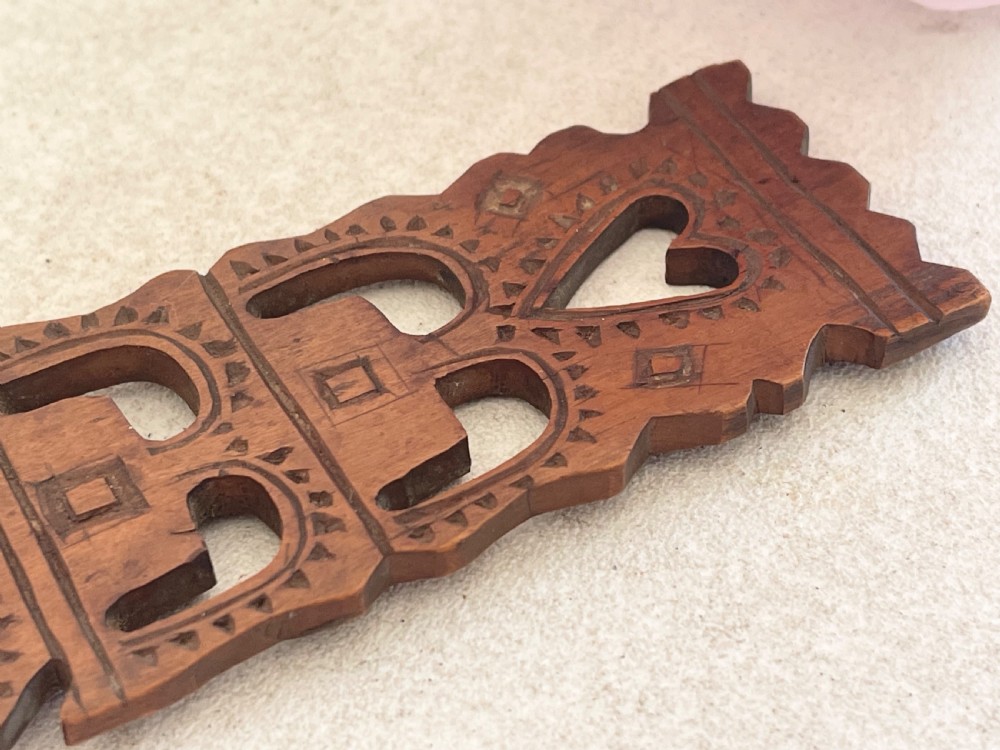 A hand-carved dark wood Welsh lovespoon with geometric chip-carved detailing, a pierced heart cutout at the top, and a smoothed spoon bowl. View VI