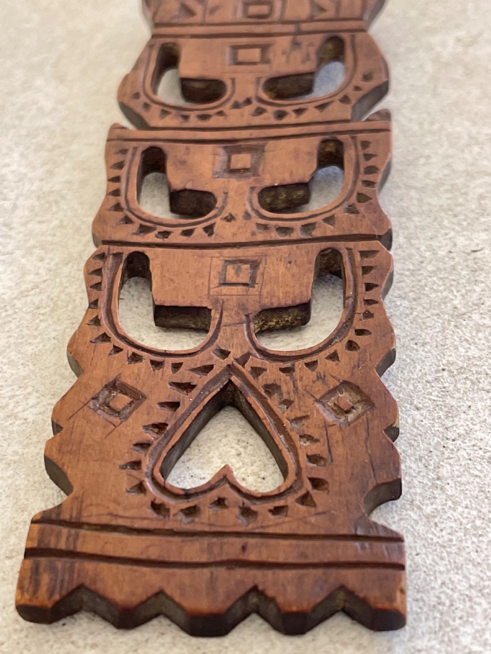 A hand-carved dark wood Welsh lovespoon with geometric chip-carved detailing, a pierced heart cutout at the top, and a smoothed spoon bowl. View VII