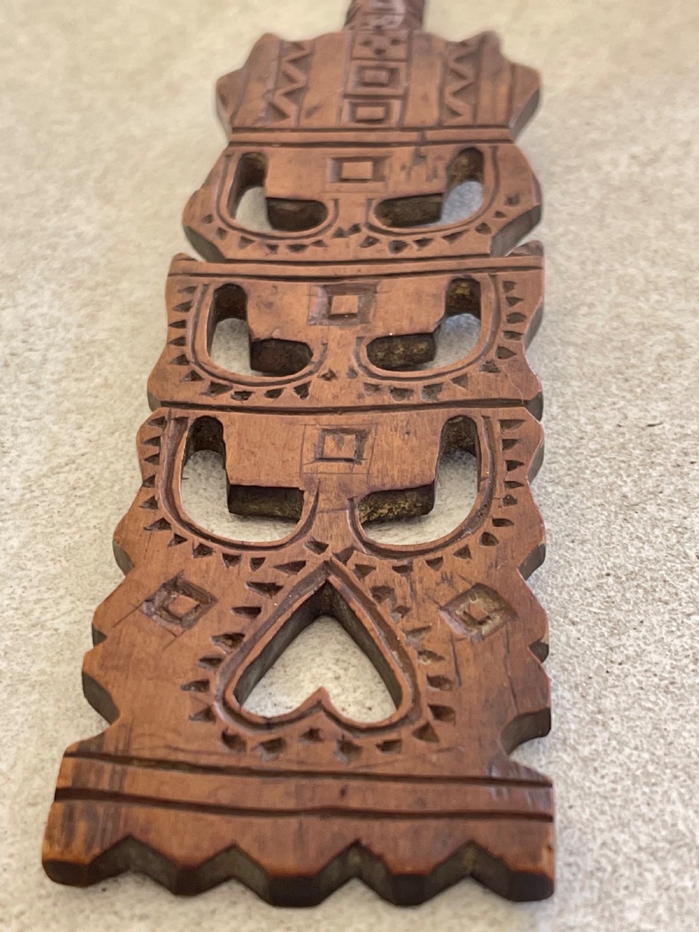 A hand-carved dark wood Welsh lovespoon with geometric chip-carved detailing, a pierced heart cutout at the top, and a smoothed spoon bowl. View VIII