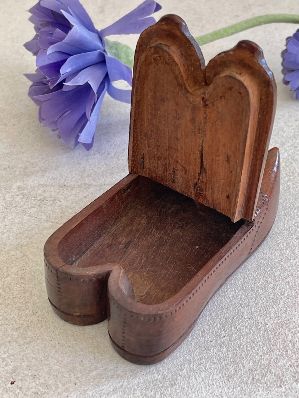 A carved brown wooden double shoe-shaped snuff box featuring stippled geometric patterns, metal spring hinges, and an inset oval miniature portrait of a lady on top. View II