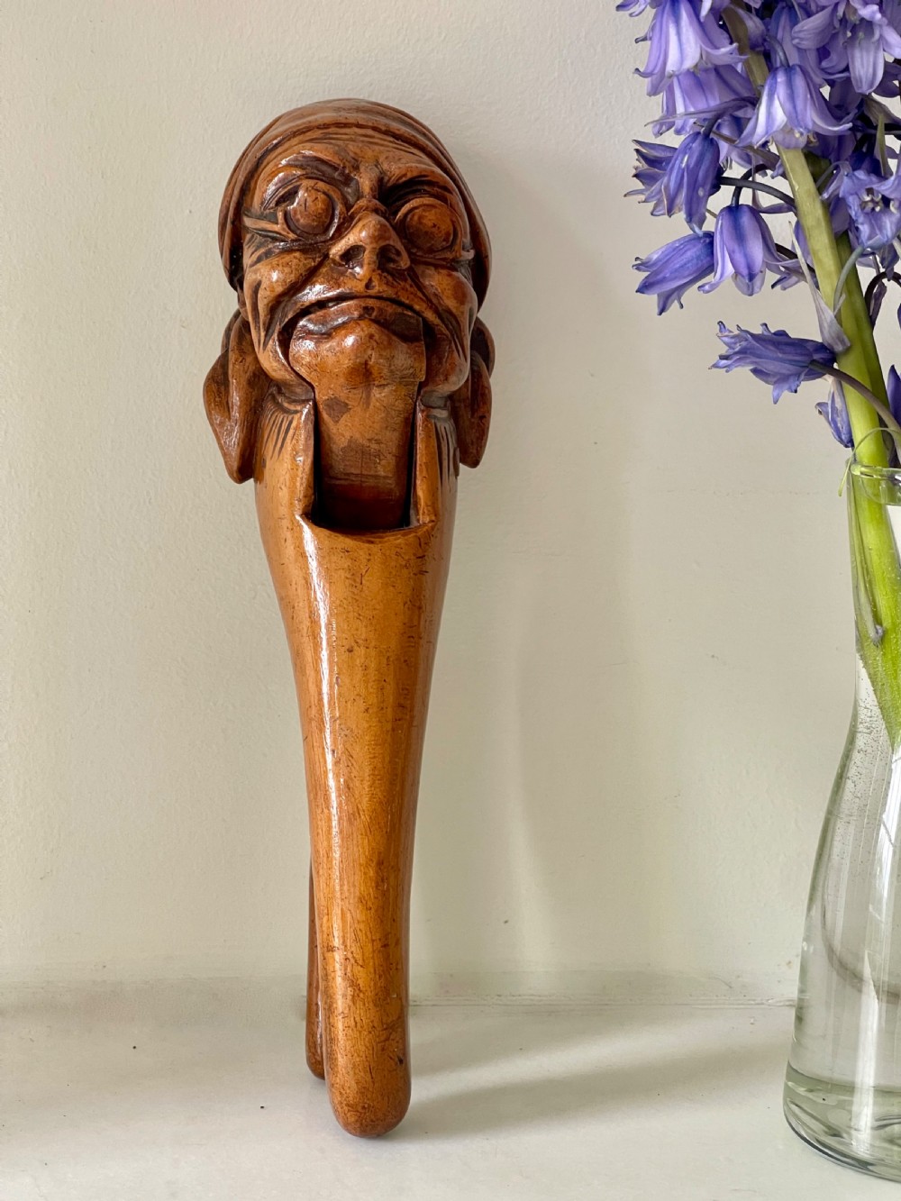 A hand-carved wooden lever nutcracker sculpted into a human head wearing spectacles and a soft cap. View III