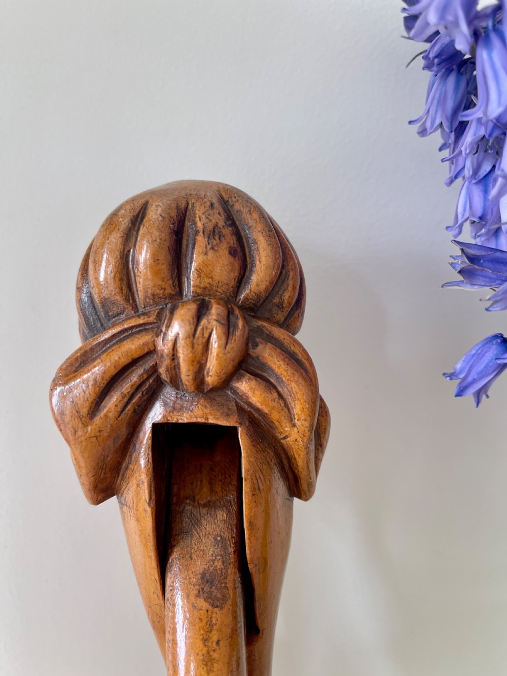 A hand-carved wooden lever nutcracker sculpted into a human head wearing spectacles and a soft cap. View V