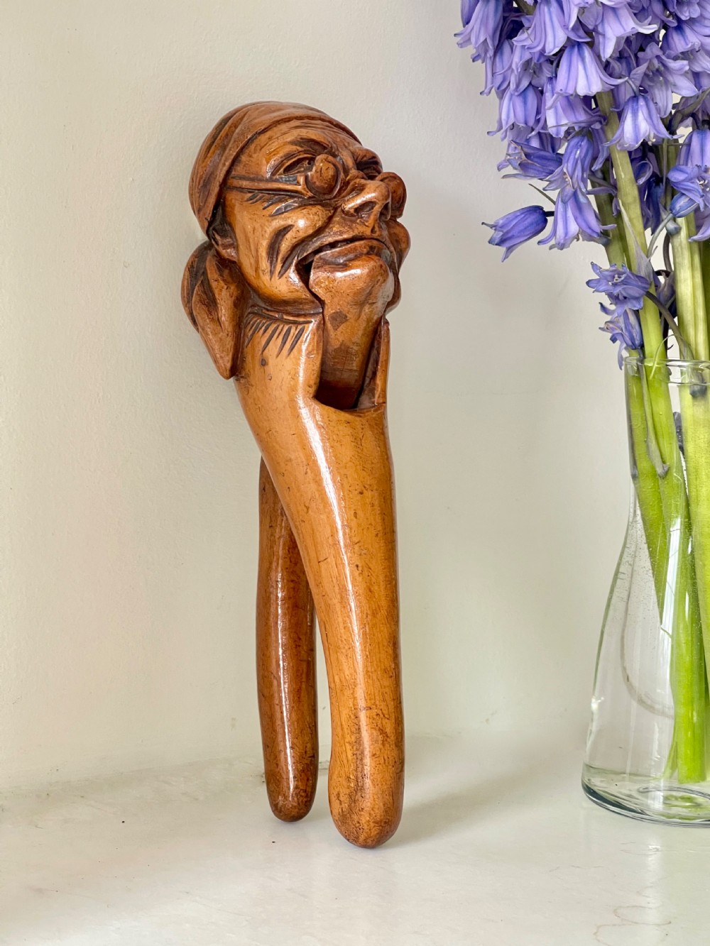 A hand-carved wooden lever nutcracker sculpted into a human head wearing spectacles and a soft cap. View VII
