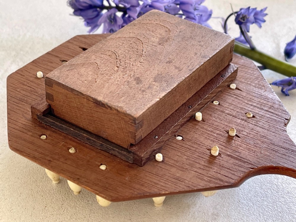 A paddle-shaped wooden peg solitaire board featuring numbered slots and carved bone pegs. View VIII