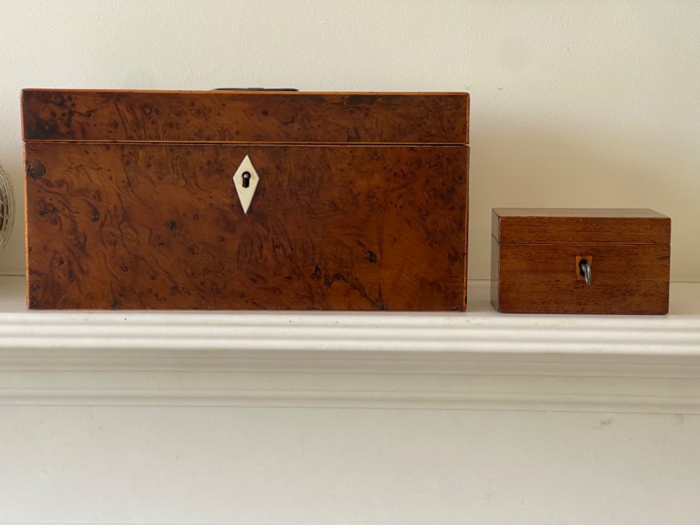 An open small wooden tea caddy featuring two internal compartments with turned knobs, a blue-lined interior lid, and a key inserted into the front lock. View II