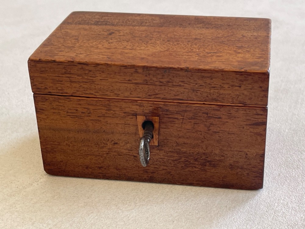 An open small wooden tea caddy featuring two internal compartments with turned knobs, a blue-lined interior lid, and a key inserted into the front lock. View IV