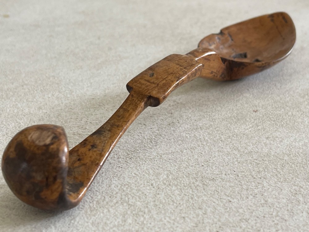 A hand-carved antique wooden spoon featuring a shallow pointed bowl, a stepped shaft, and a curved terminal hook. View VII