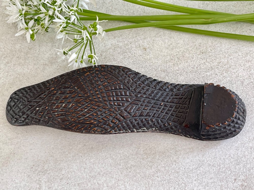 A carved wooden knitting sheath crafted in the shape of a shoe sole with a polished dark surface. View IV