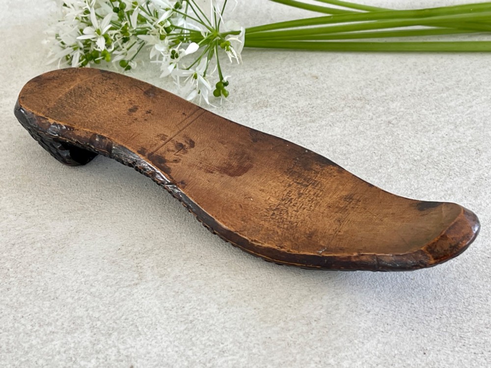 A carved wooden knitting sheath crafted in the shape of a shoe sole with a polished dark surface. View V