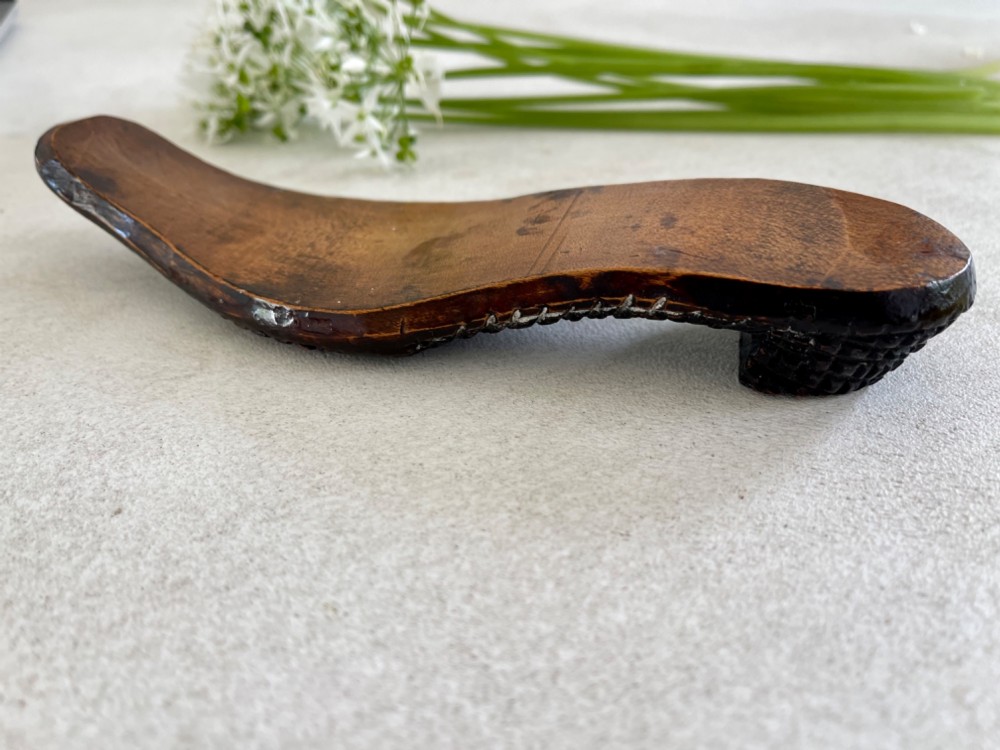 A carved wooden knitting sheath crafted in the shape of a shoe sole with a polished dark surface. View VI
