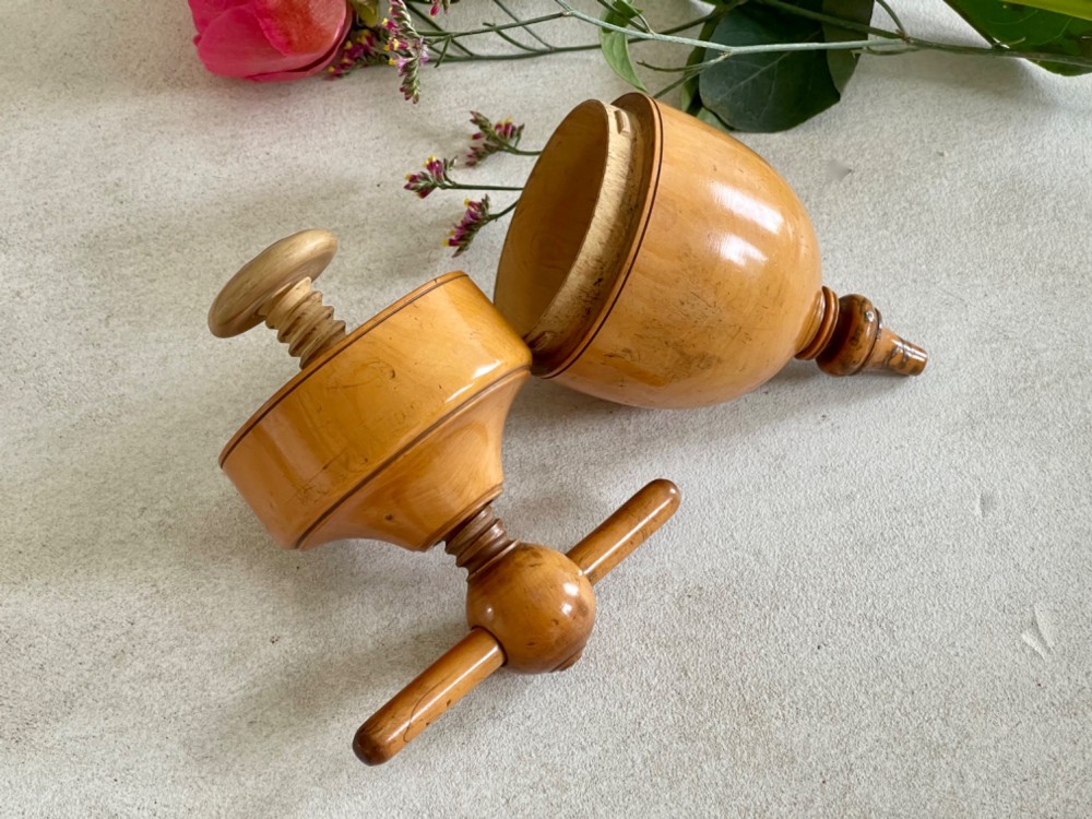 A turned wooden urn-shaped lemon squeezer with a threaded screw handle and spout tip in a warm amber finish. View II