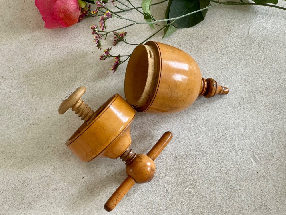 A turned wooden urn-shaped lemon squeezer with a threaded screw handle and spout tip in a warm amber finish. View V