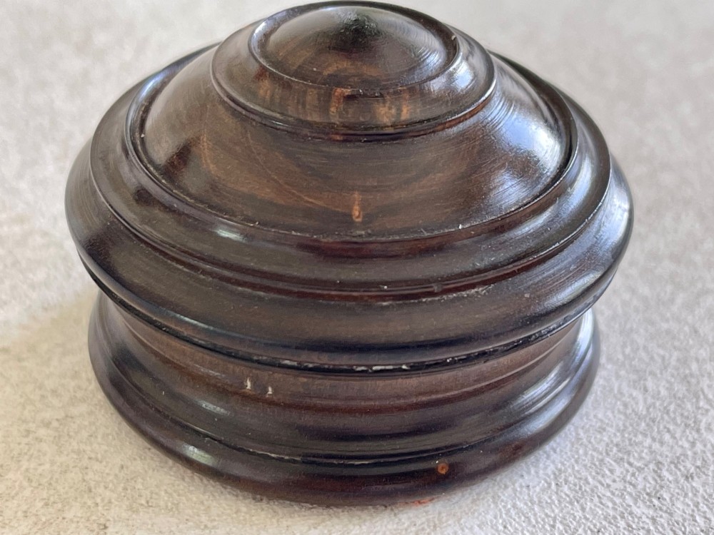 A turned dark lignum vitae wooden case opening to reveal a pocket compass and solar sundial beneath a domed glass lens. View II