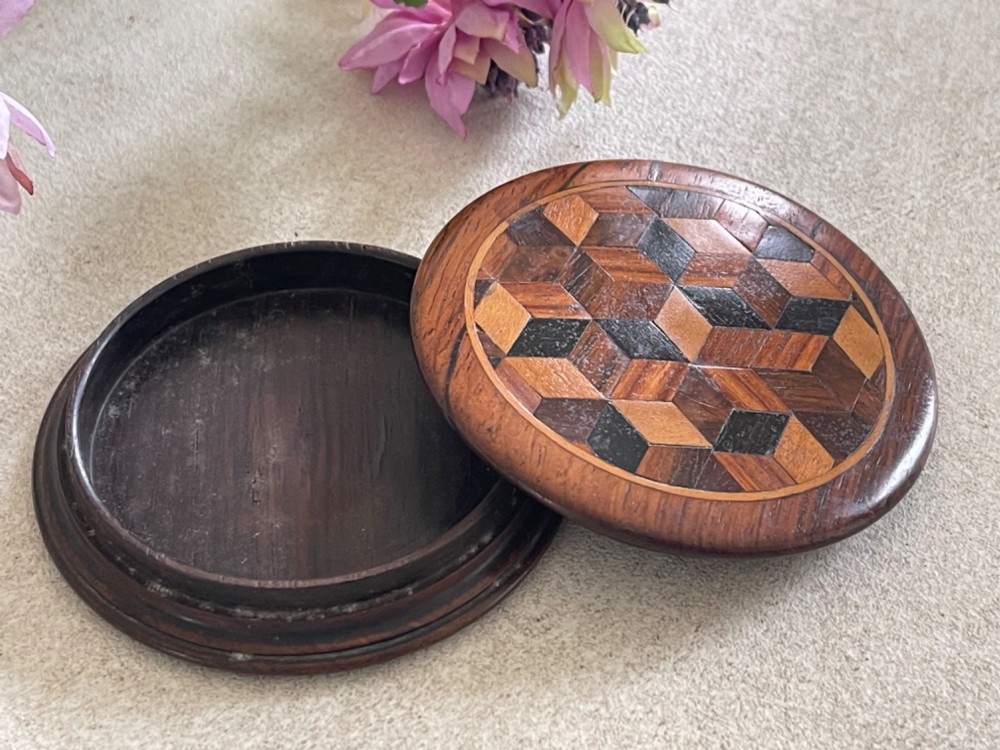 A circular antique wooden snuff box with a lid inlaid in a geometric tumbling block parquetry pattern. View III