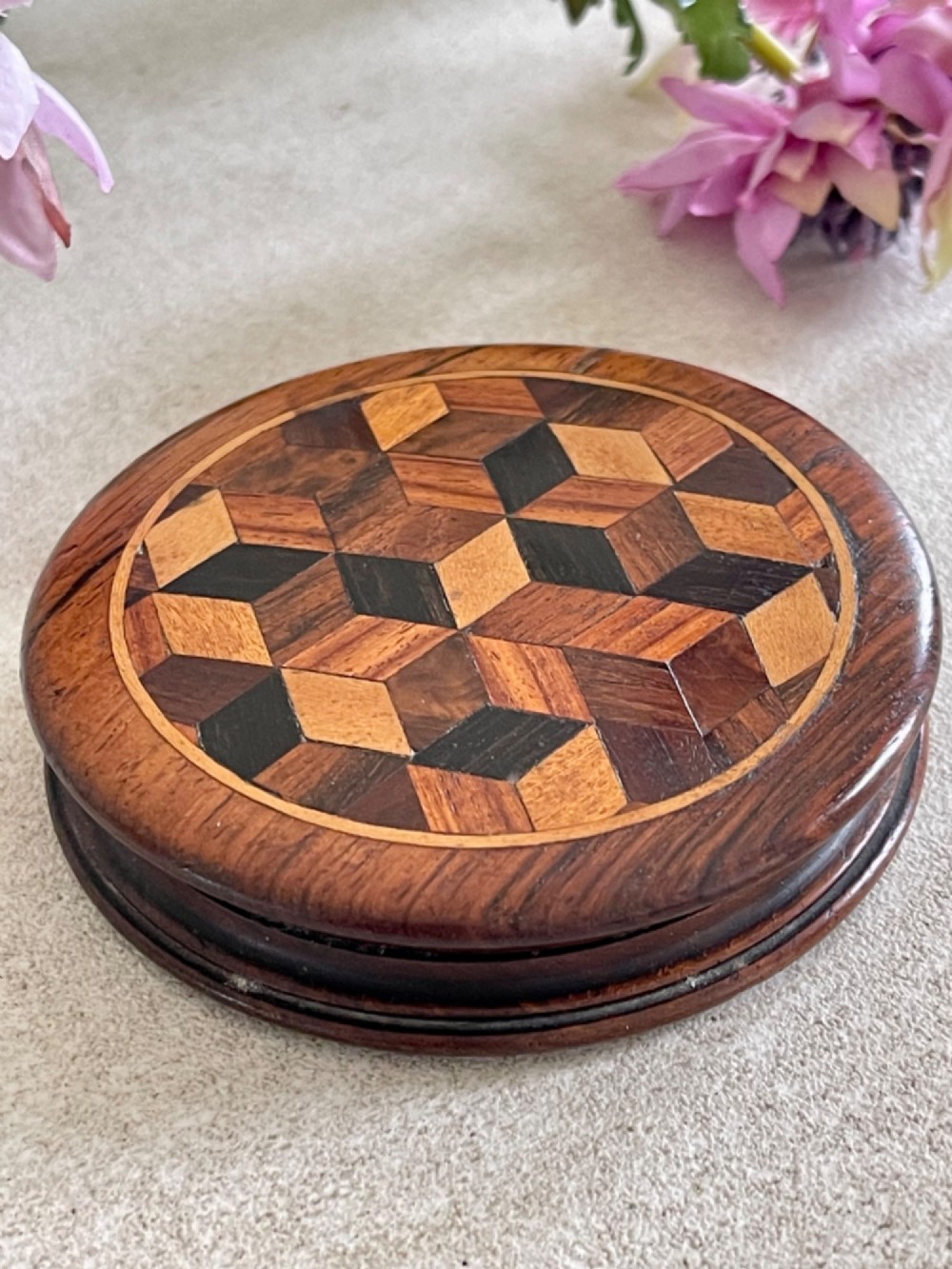 A circular antique wooden snuff box with a lid inlaid in a geometric tumbling block parquetry pattern. View IV