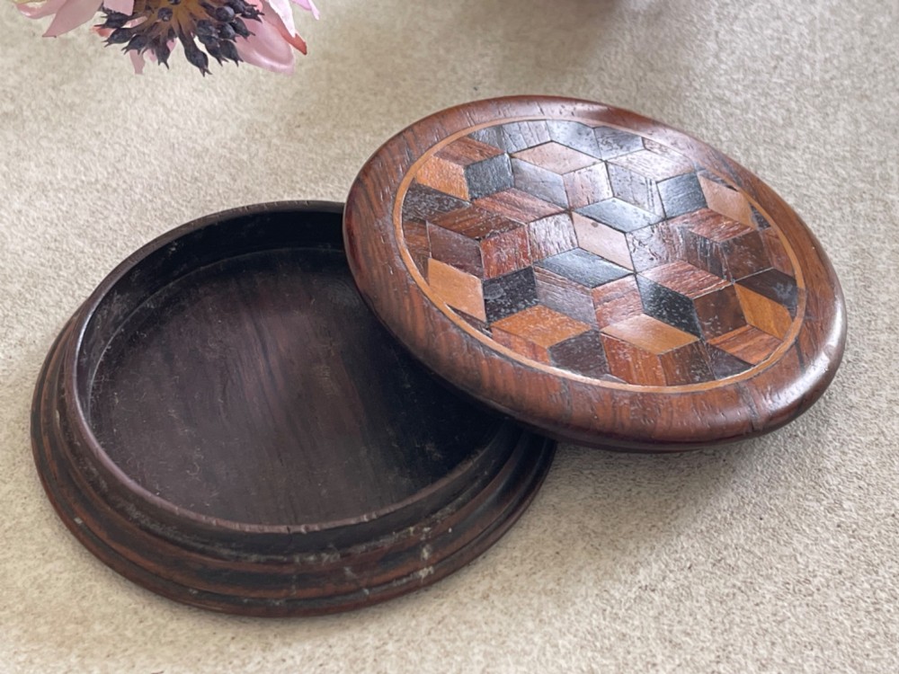 A circular antique wooden snuff box with a lid inlaid in a geometric tumbling block parquetry pattern. View V