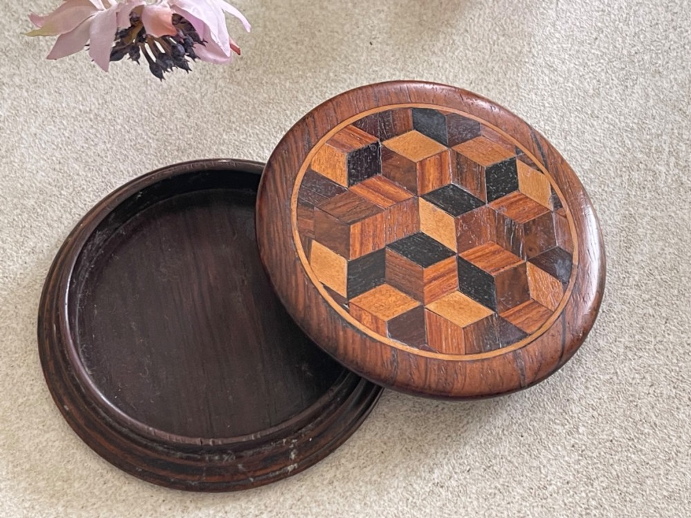 A circular antique wooden snuff box with a lid inlaid in a geometric tumbling block parquetry pattern. View VIII
