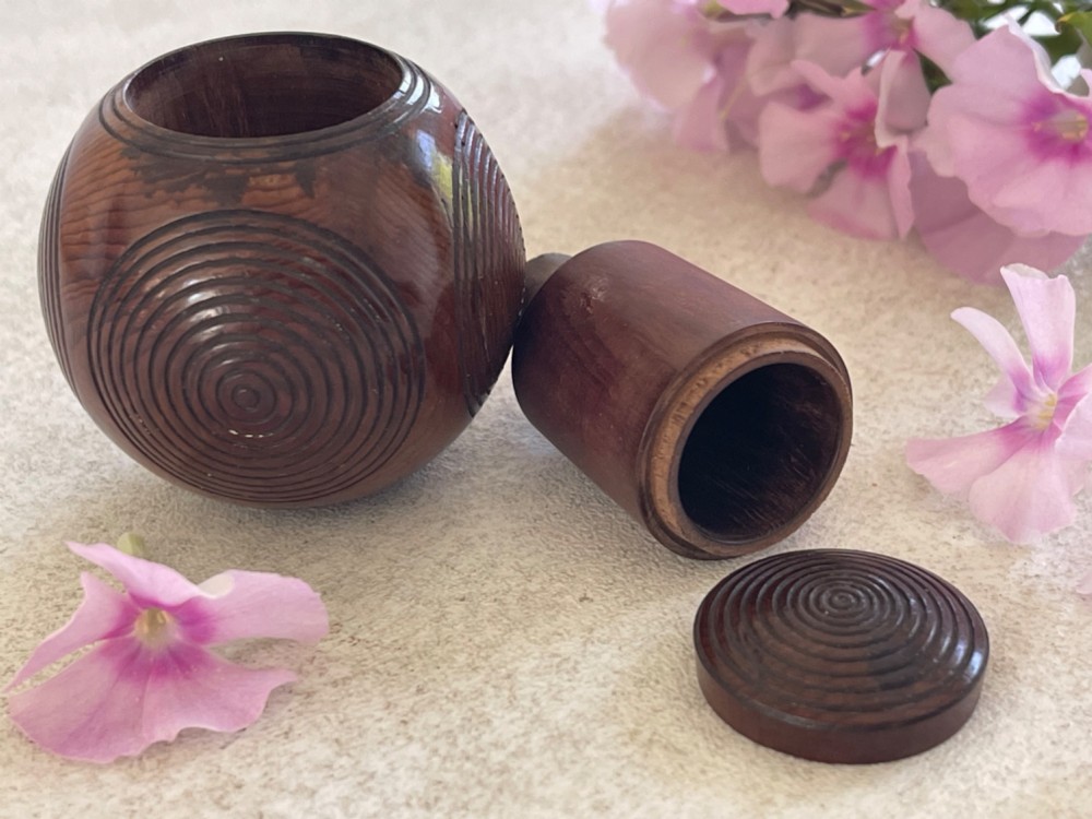 A spherical carved dark brown wooden puzzle ball featuring concentric circular grooves on its outer surface. View III