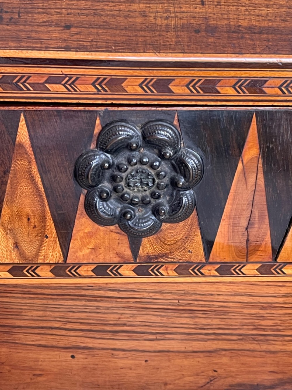 A rectangular Georgian wooden tea caddy featuring geometric triangular parquetry inlay across the front facade and a bevelled lid with a keyhole escutcheon. View VI