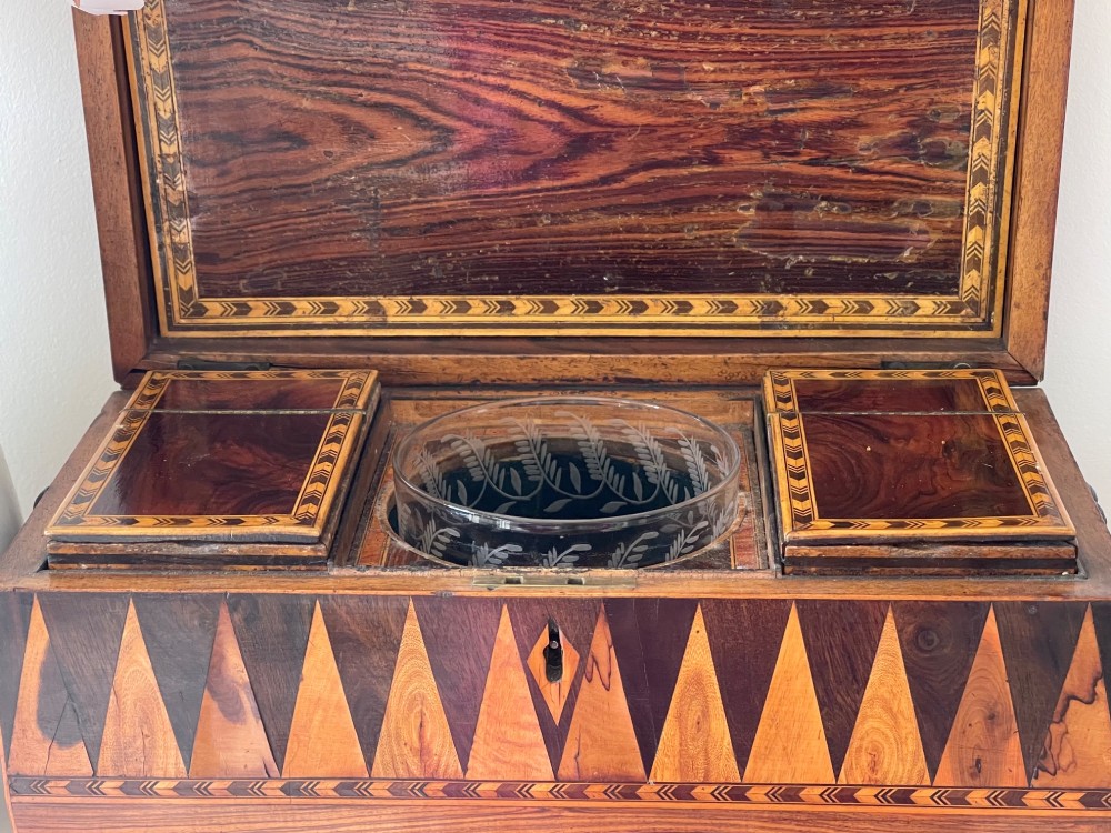 A rectangular Georgian wooden tea caddy featuring geometric triangular parquetry inlay across the front facade and a bevelled lid with a keyhole escutcheon. View VIII