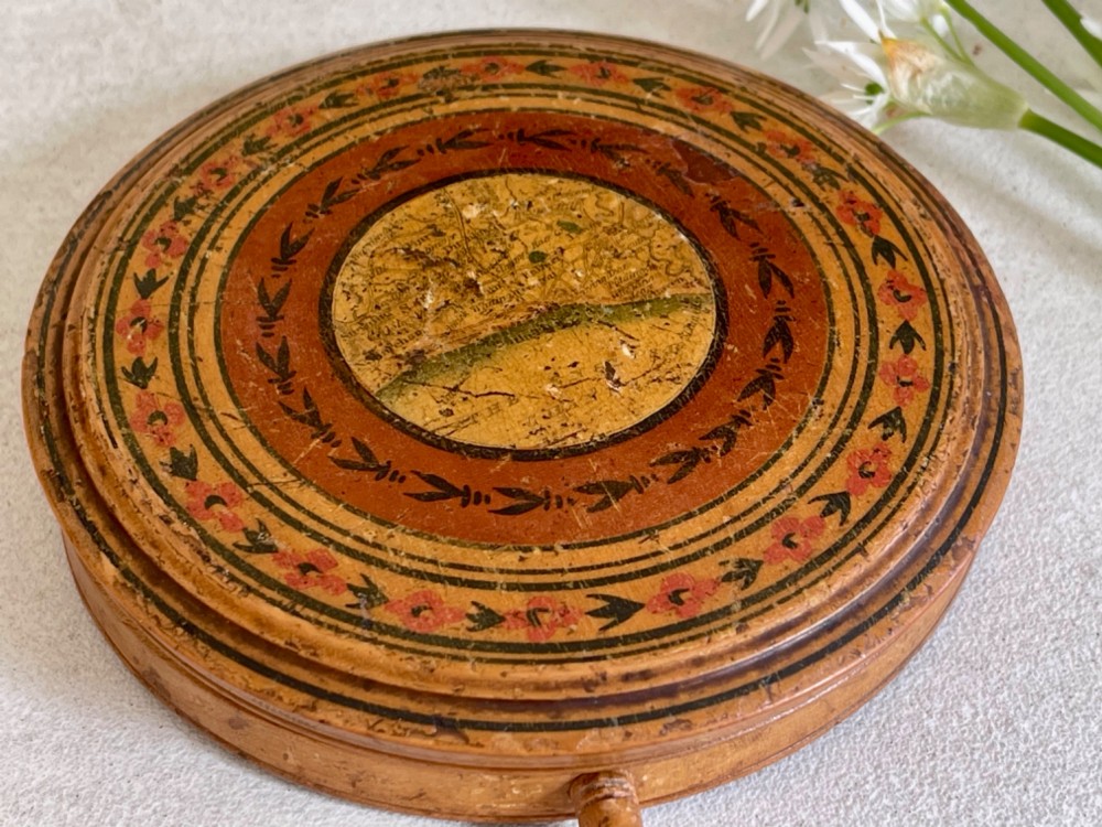 A circular wooden travelling mirror featuring concentric red and black decorative bands around the lid and a turned wood handle. View VII