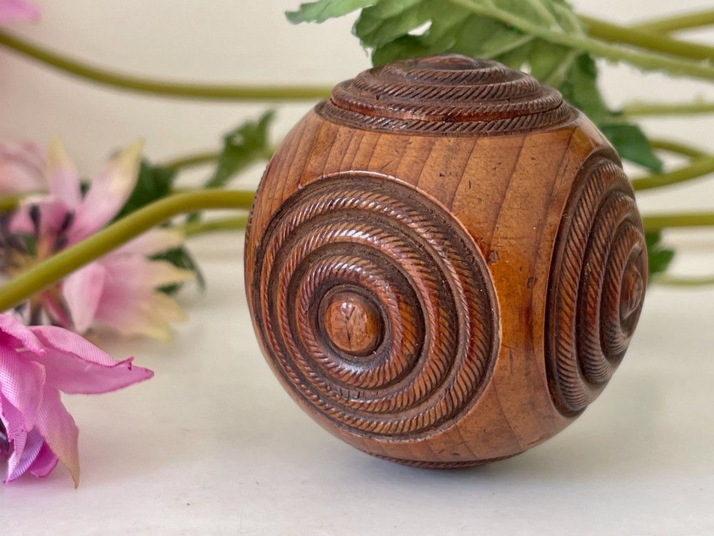A spherical turned wood puzzle ball featuring concentric carved rope twist rings and visible timber grain patterns.