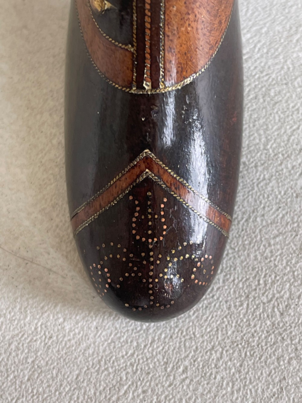A carved wooden snuff box crafted in the shape of a high-heeled shoe featuring brass pin decoration and double compartments. View V