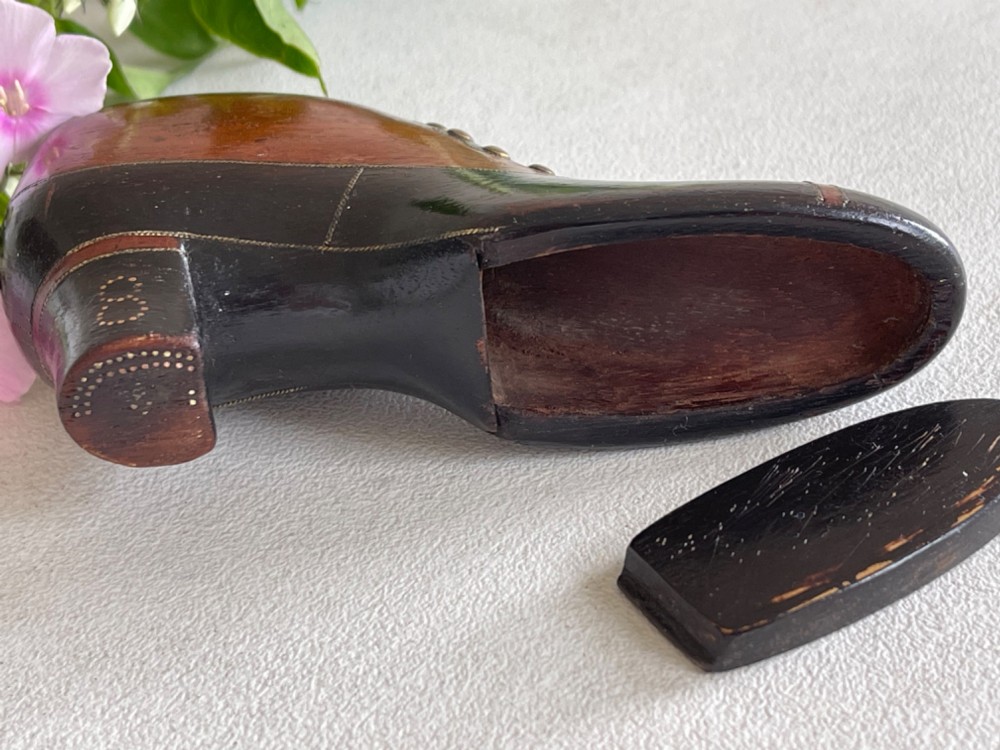 A carved wooden snuff box crafted in the shape of a high-heeled shoe featuring brass pin decoration and double compartments. View VI
