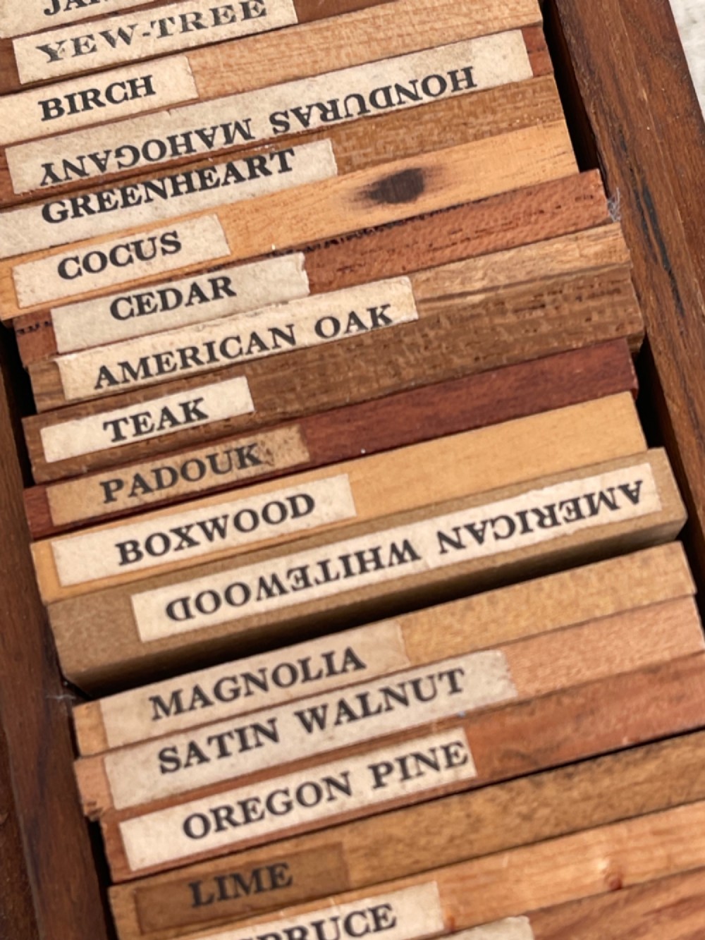 An open rectangular wooden presentation box containing labelled timber sample slats from an early twentieth century London wood merchant. View IV