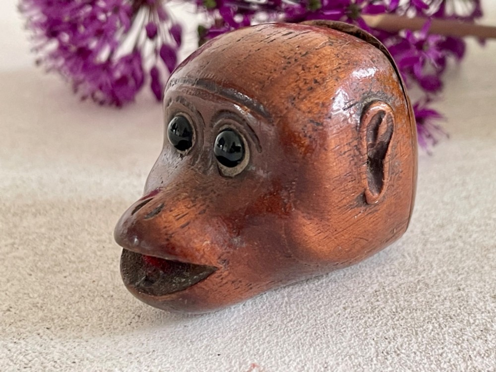 A carved wooden snuff box in the form of a monkey head with inset black glass eyes.